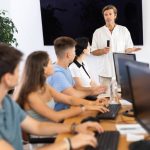 Image of a male instructor conducting software development courses to group of people.